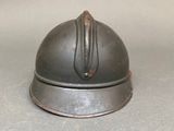 a small metal helmet on a table with a white background