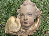 une statue représentant un enfant tenant une pomme, posée sur l'herbe