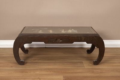 une table basse avec un plateau en verre posée sur un parquet en bois massif