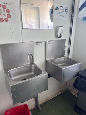 deux lavabos et une poubelle dans des toilettes publiques