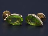 une paire de boucles d'oreilles en verre vert posées sur une surface noire