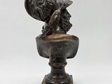 a bronze statue of a bird on a pedestal with a white background