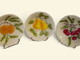 three small plates with fruit designs on them on a white surface