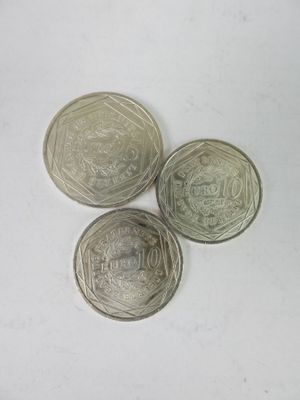 trois pièces d'argent posées l'une à côté de l'autre sur une surface blanche