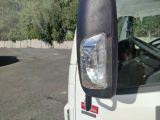 a white truck parked in a parking lot with trees in the background