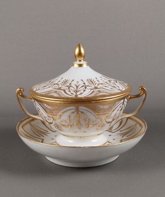 une tasse et une soucoupe blanches et dorées posées sur une soucoupe
