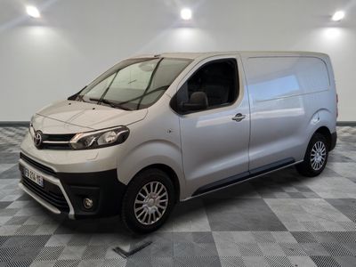La camionnette argentée est garée sur un sol en carrelage à damier.
