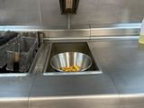 plan de travail en acier inoxydable dans une cuisine professionnelle équipée d'une friteuse et d'un évier
