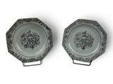 two plates with black and white designs on them on a white surface