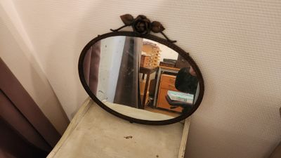 un miroir posé sur une commode près d'une fenêtre