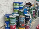 many cans of paint sitting on the ground next to a wall