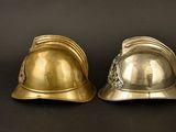 pair of brass fire helmets on a black background
