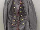 une veste noire avec des bordures et des boutons roses, suspendue à un cintre