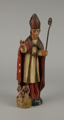 figurine représentant un homme vêtu d'une robe rouge, tenant un bâton et un chien