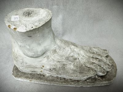 une statue blanche représentant un pied, sur laquelle est accrochée une étiquette