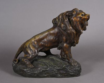 bronze statue of a lion on a rock on a gray background