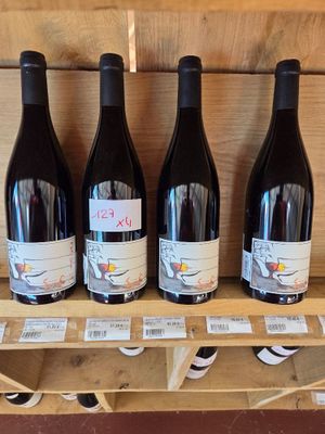 Quatre bouteilles de vin sont posées sur une étagère en bois dans un caviste.