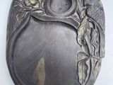 une assiette en argent ornée d'un motif représentant un oiseau et une fleur