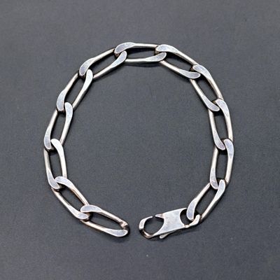 a close up of a silver chain bracelet on a black surface