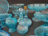 many blue glass dishes and vases on a table