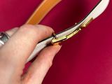 a woman ' s hand holding a leather belt with a gold buckle