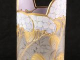 a glass vase with a gold and white design on it