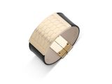 un gros plan d'un bracelet noir et doré posé sur une surface blanche