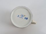 a white cup with blue writing on it sitting on a table
