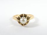 gros plan d'une bague en or avec une perle au centre