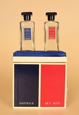 two bottles of cologne sitting on top of a box on a table