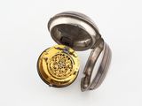 une vieille montre de poche posée sur une surface blanche