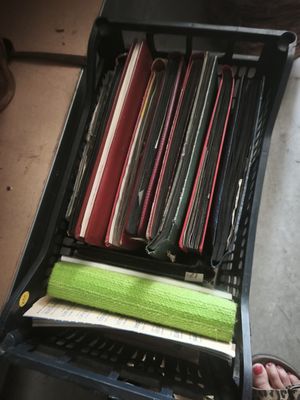 a person standing next to a black suitcase with a bunch of papers in it