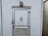 un petit bâtiment blanc avec une porte métallique et une fenêtre