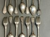 eight silverplated spoons and six forks are arranged in a row