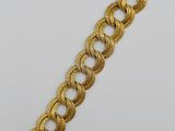 a gold bracelet with a large braid design on it