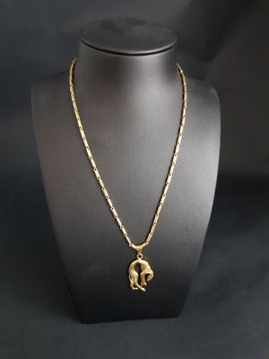 a gold plated necklace with an elephant pendant on a mannequin
