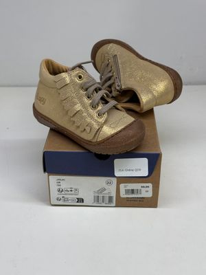 une paire de chaussures dorées posée sur une boîte en carton