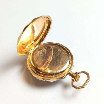 a gold pocket watch sitting on a white surface