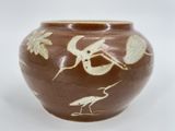 a brown vase with birds and leaves on it