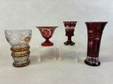 quatre vases en verre de couleurs différentes posés sur une surface blanche