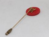 a red lapel pin with a gold bow on it