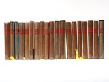 several old books are lined up on a shelf on a white surface