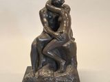 une statue représentant un couple assis sur un rocher, enlacés