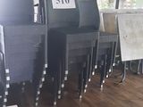 Dans un restaurant, des tables et des chaises sont alignées, et un menu est affiché au mur.