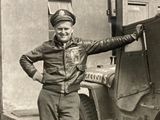 a black and white photo of a man standing next to a jeep