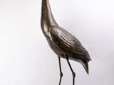 statue en bronze représentant un oiseau perché sur un rocher, sur fond blanc