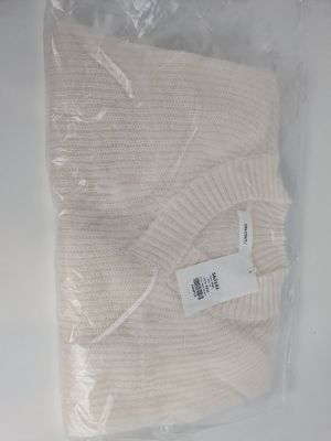 un pull blanc dans un sac en plastique posé sur une table