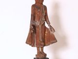 statue en bois représentant une personne debout sur un socle, sur fond blanc