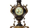 a black and gold clock on a stand on a white background