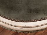an upholstered chair with a green upholstered seat and beaded trim